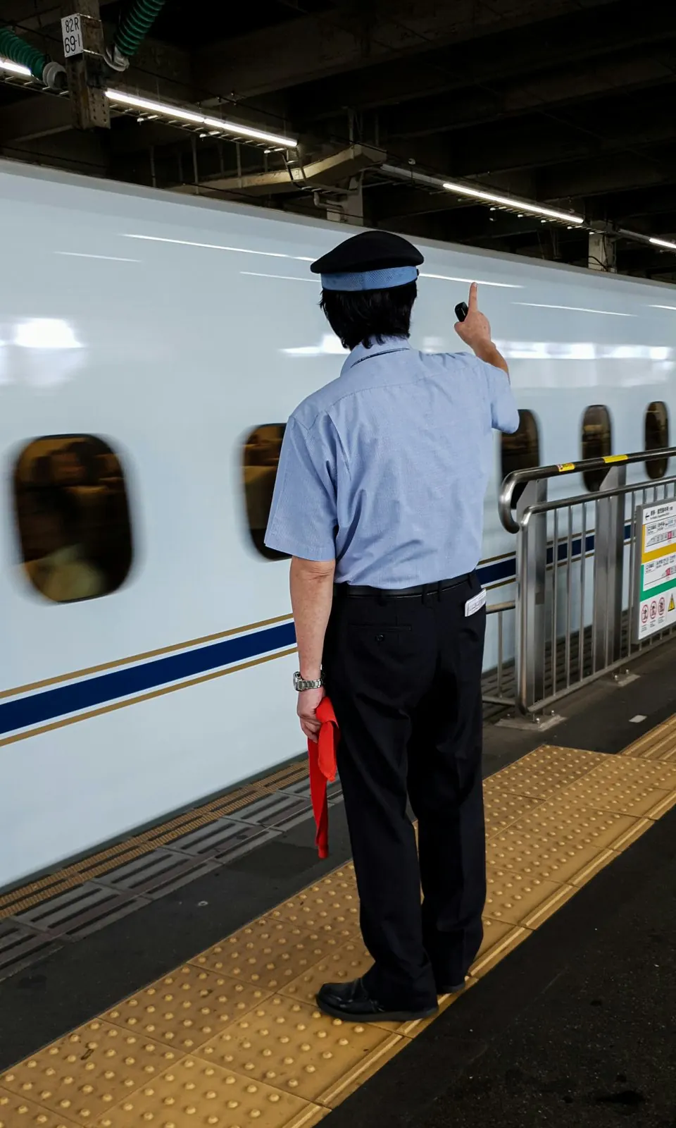 新幹線のホームで指差し確認をする駅員の後ろ姿
